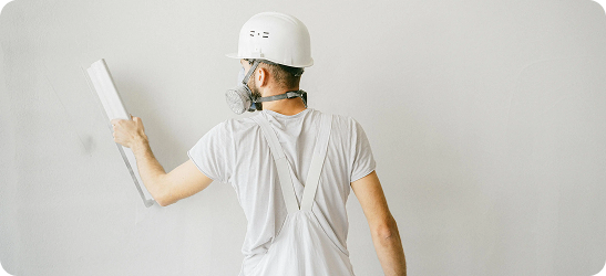 Plasterer applying plaster to wall