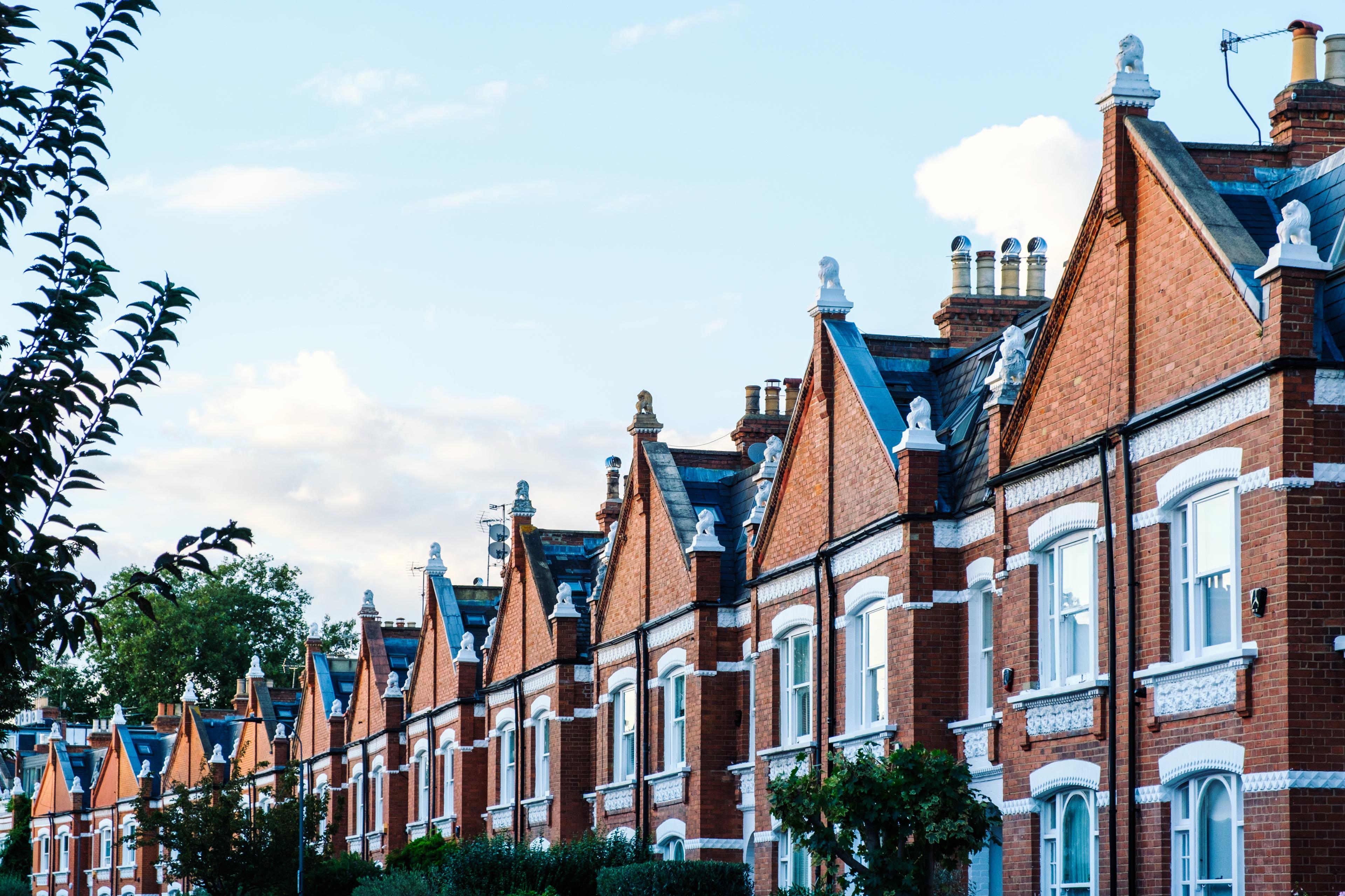 Terraced houses with red brick facade and white ornaments are forming a beautiful residential street in london